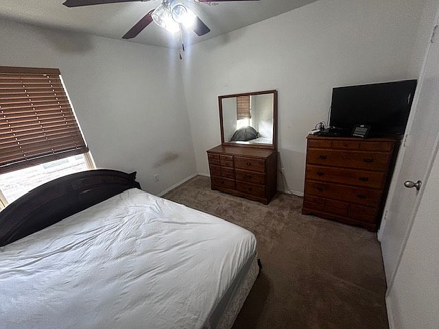 The whole bedroom with a mattress and two dressers and a tv