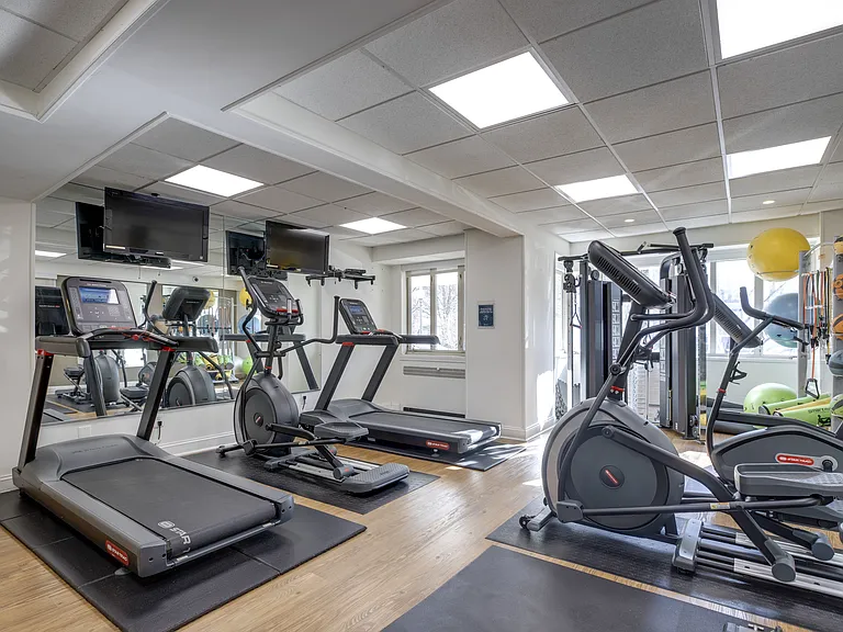 A gym with treadmills, elliptical machines, and other exercise equipment at 2100 Connecticut