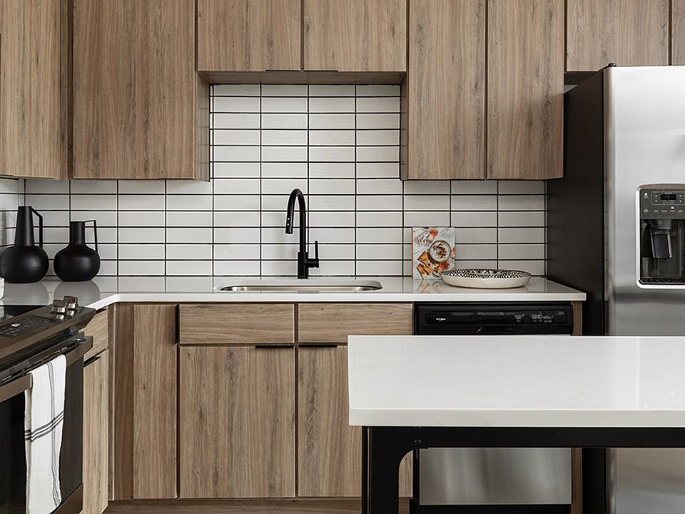 Apartment kitchen with stainless steel appliances, quartz countertops and wood-style flooring.