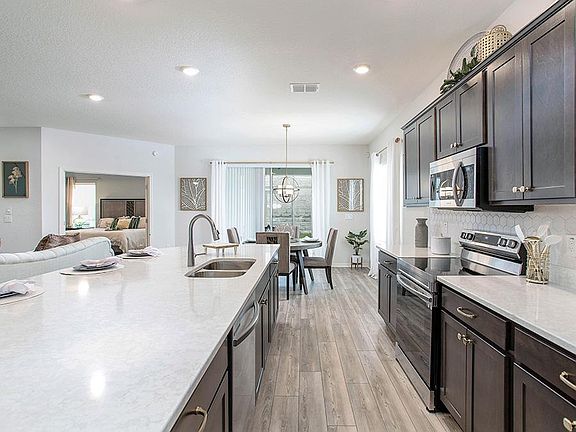 Open kitchen with counter-height island and stainless steel appliances - Shelby home plan by Highlan
