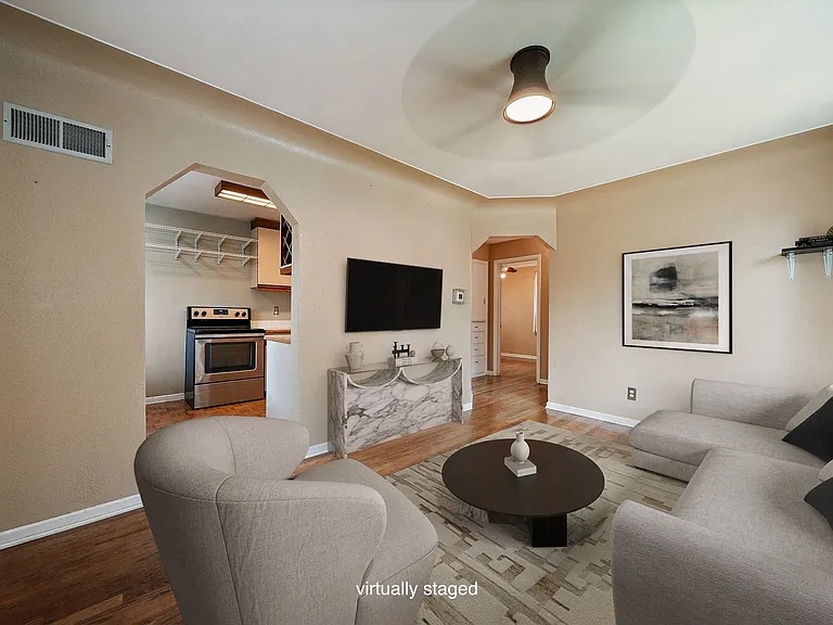 Living room off kitchen (virtually staged photo) has a fan and many windows both facing East and South