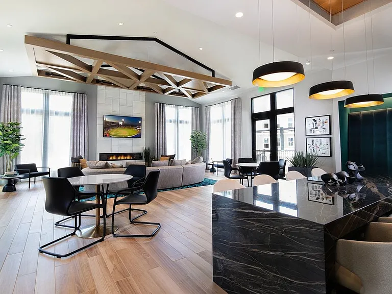 Resident lounge with multiple seating areas, TV, fireplace, and entertaining kitchen