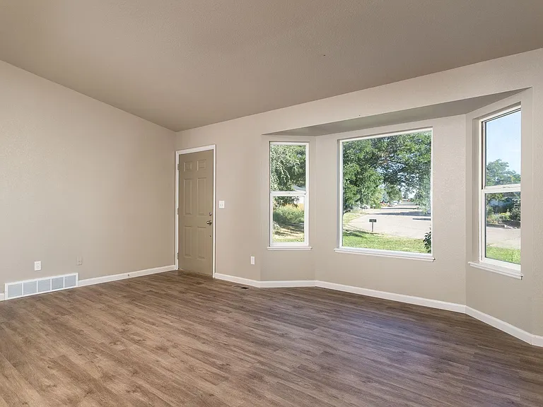 Living room w/ large bay window and vaulted ceilings and new LVP flooring.