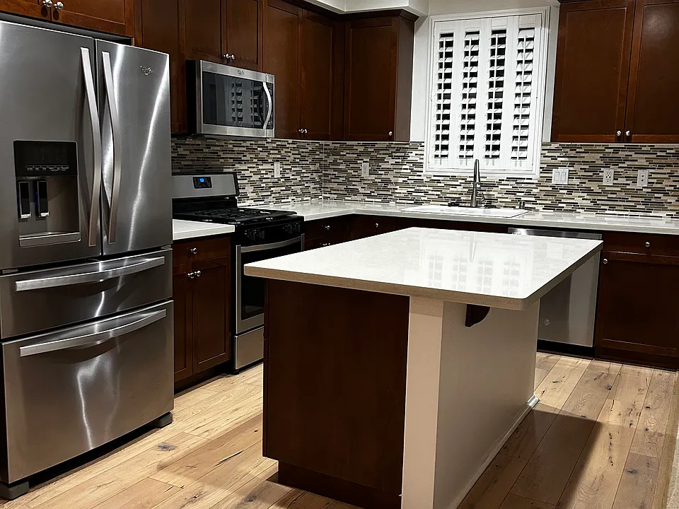 Kitchen includes all appliances and features an island with a breakfast counter. (virtually staged to reflect updated flooring)