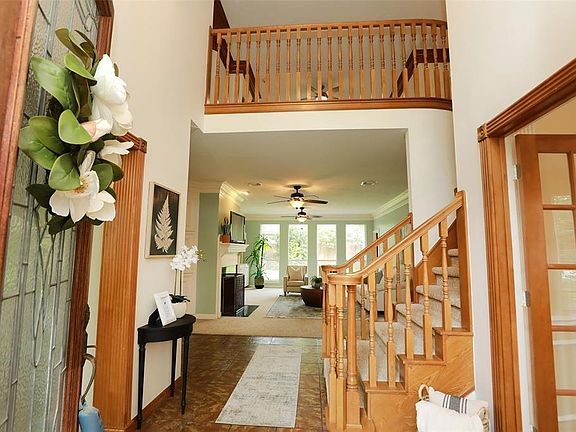 ANOTHER ENTRY HALL VIEW: From the front door you have a clear view through the family room and to the lush backyard beyond. The curved stairway leads to the upstairs game room, and you can see the curved overlook from the game room to the two story e