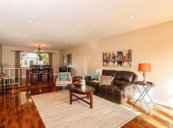 Spacious living room with wood look flooring, recessed lights and tall base moulding.