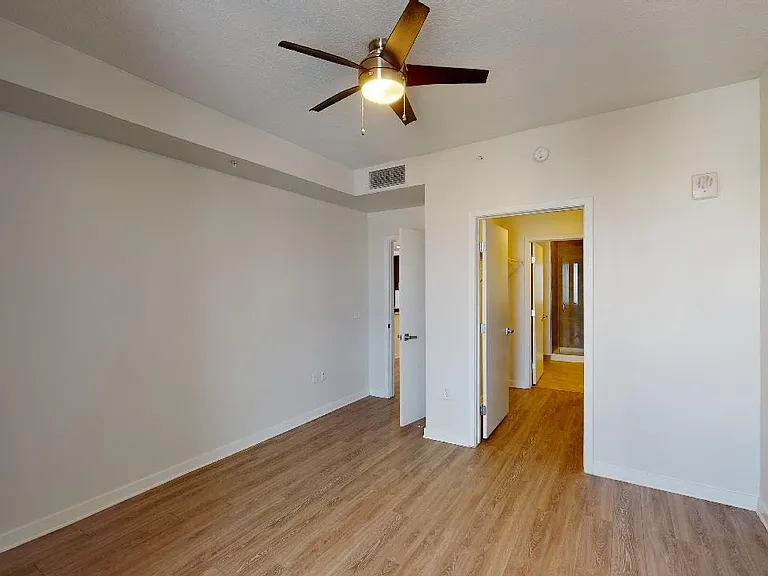 Spacious apartment bedroom with large closet and wood-style flooring.
