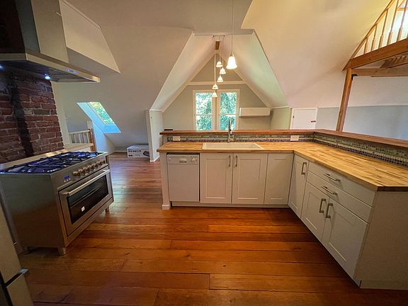 large open kitchen with 5 burner chefs gas range. And a kitchen nook for a table.