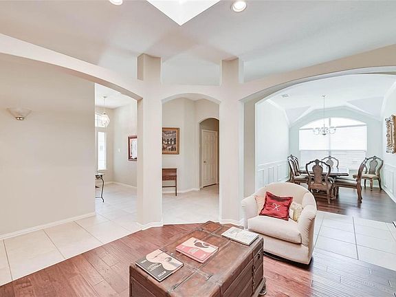 Living area with arched walkways, a notable chandelier, light wood finished floors, and plenty of natural light