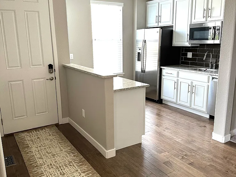 Enjoy a well-appointed kitchen with stainless steel appliances, including a gas stove, refrigerator, dishwasher, and microwave, complemented by granite countertops and attractive laminate flooring.