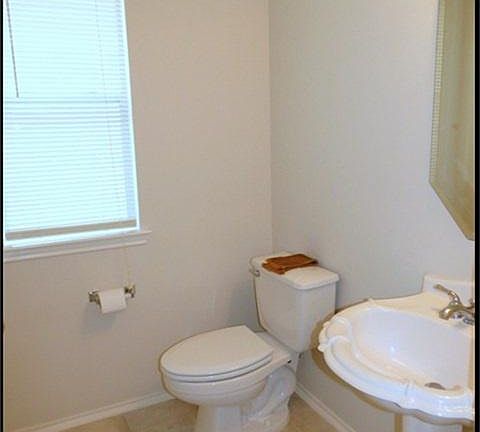 Half bath with pedestal sink and tile floors.