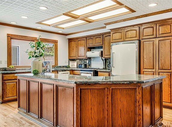 Country kitchen in the great room includes a large island. Custom cabinetry with granite counters and backsplash. High end Heartland appliances from Canada include a stove with gas cooktop and convection oven.
