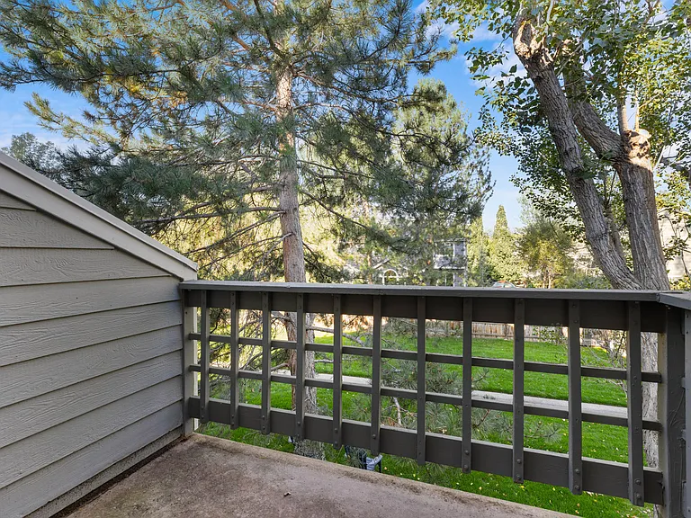Private balcony overlooking mature trees and greenbelt with no directly adjacent neighboring units, creating a peaceful outdoor retreat.