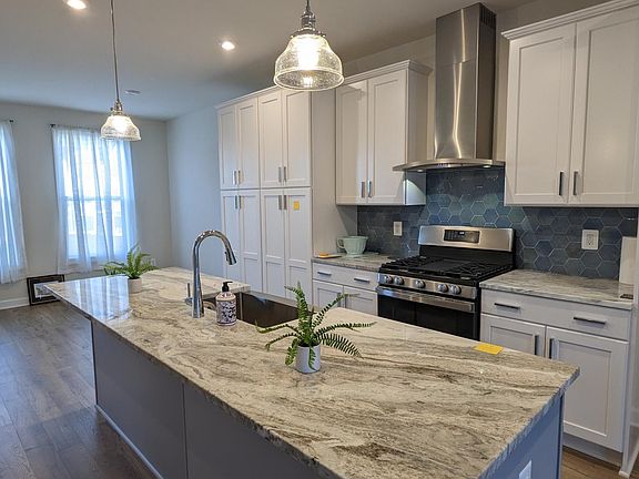 Kitchen w upgrades: stainless GE appliances, blue-tile backsplash, granite island, pantry, exhaust hood above gas stove...
