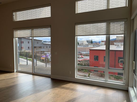 Bright space with kitchen and living areas banked by (nearly) floor-to-ceiling windows, one of which opens onto one of the 3 decks in the unit.