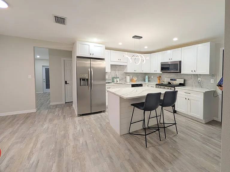 Spacious kitchen with an oversized peninsula, stainless steel appliances, and ample shaker cabinetry for storage.