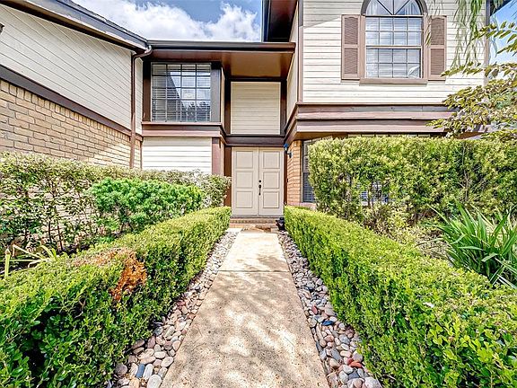 The pathway leading to the covered front porch is flanked with lush shrubs and bushes.