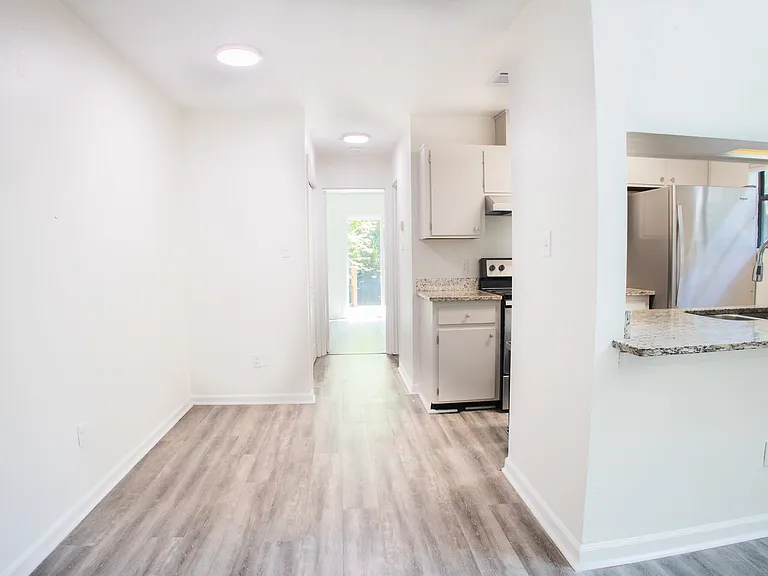 Open hallway leading to kitchen and rear entrance and bedroom