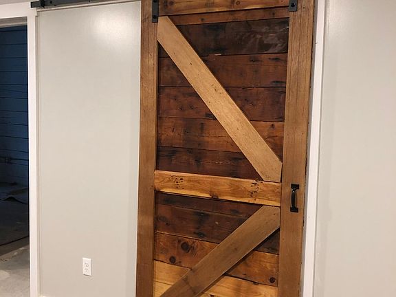 Custom made, reclaimed wood barn door provides privacy for the bathroom and style to the apartment.