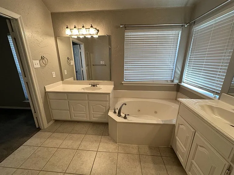 Master bath features a jetted spa tub and his and her vanity areas.
