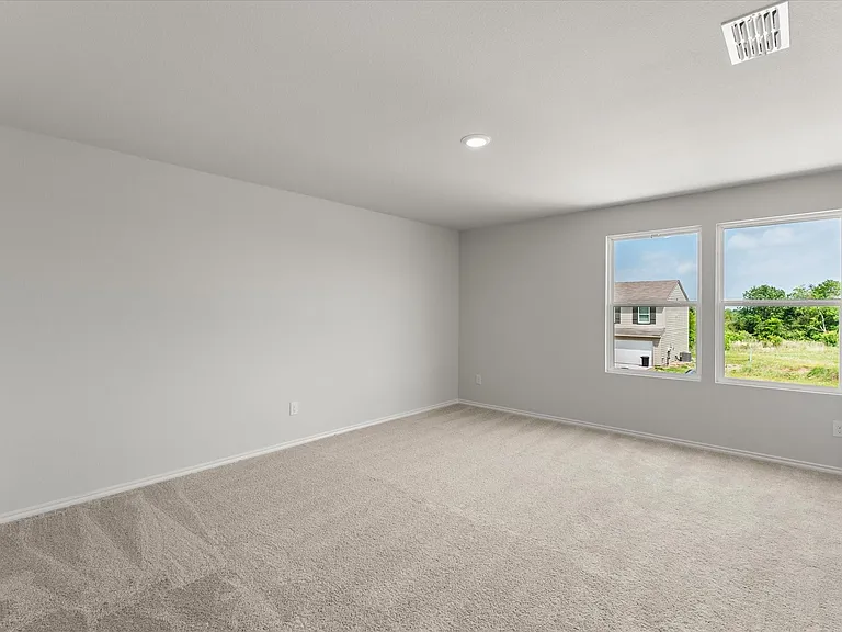Primary bedroom featuring neutral carpeting, light gray walls, two ample windows, and recessed ceiling lighting