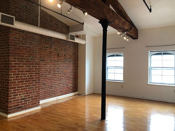 `One side of the large living room - exposed brick with lots of natural light!