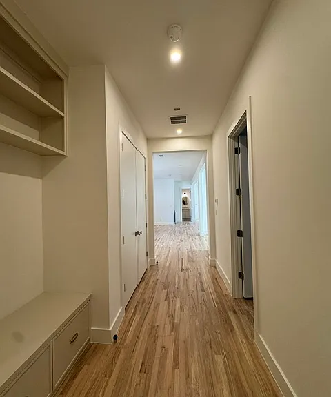 garage entry view with 1st bedroom to the right and the kitchen further down on the left