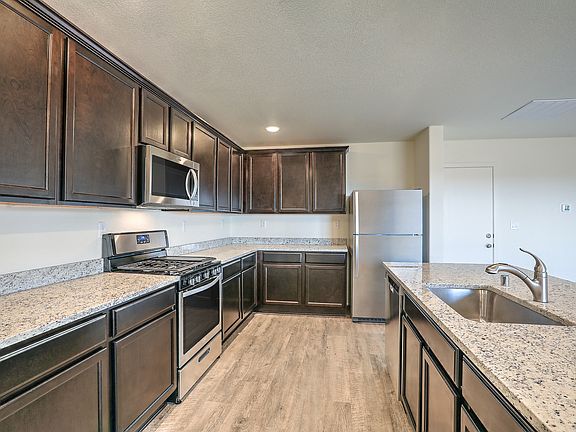 Intentionally designed kitchen with wood-style flooring, espresso cabinets, and granite countertops.