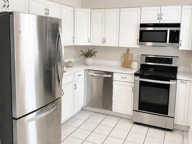 Kitchen with white cabinetry, stainless steel appliances, quartz countertops, and ceiling fan.