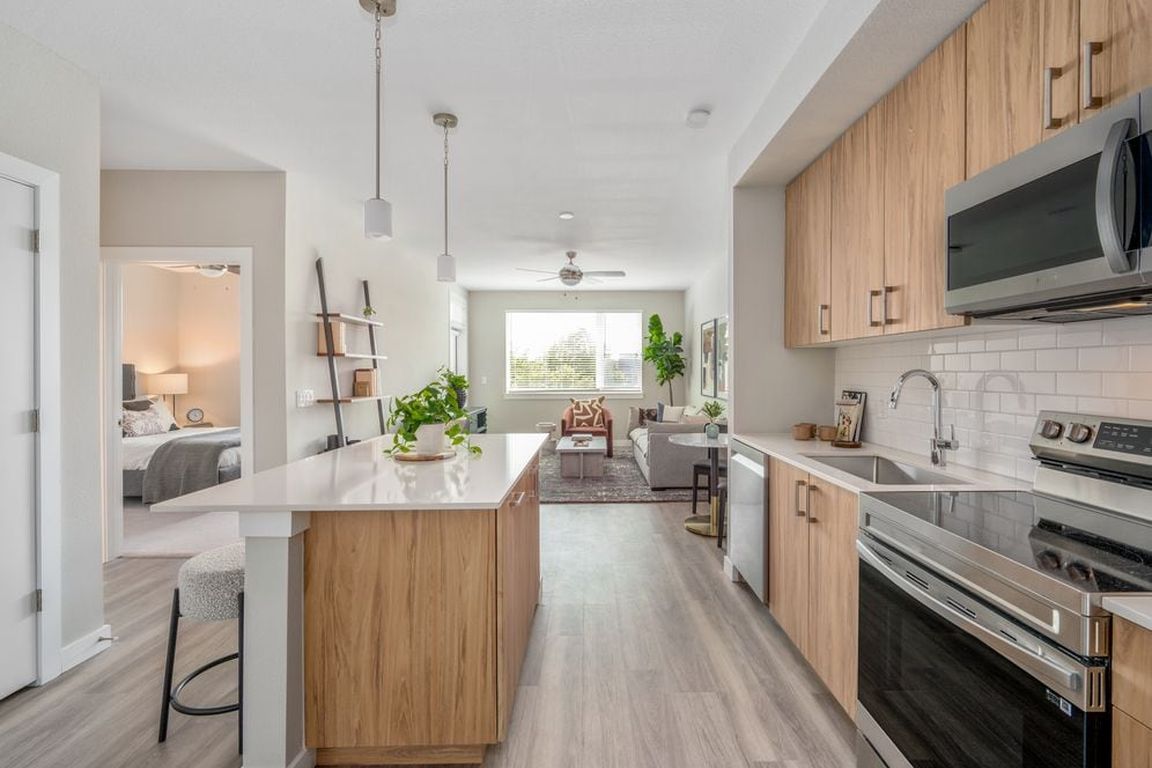 Kitchen with oak cabinetry, stainless-steel appliances, pendant lighting, hard-surface flooring and granite countertops