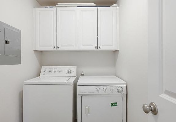 Full size Washer and Dryer in a spacious supply room with built in cabinetry