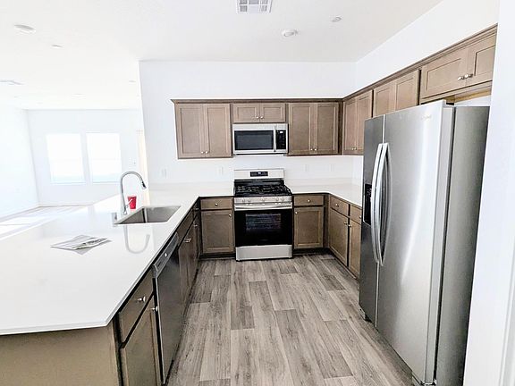 Kitchen with gas range, microwave, dishwasher, refrigerator, shaker cabinets