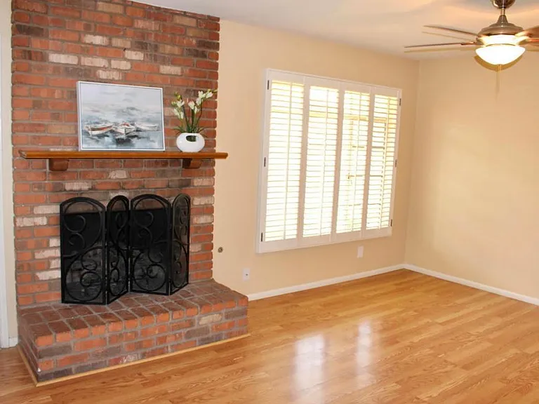 living space with gas fireplace, shutters, laminate floors and ceiling fan