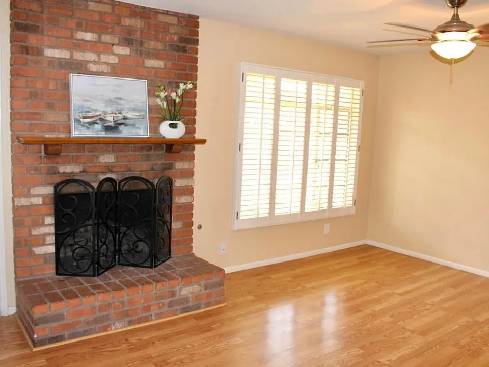 living space with gas fireplace, shutters, laminate floors and ceiling fan