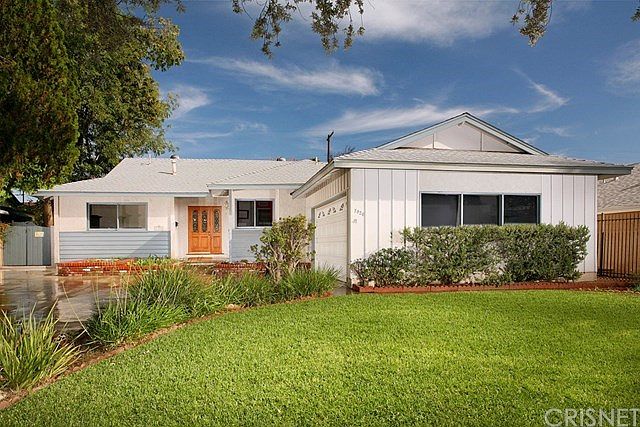 The lush green lawn, mature landscaping, towering