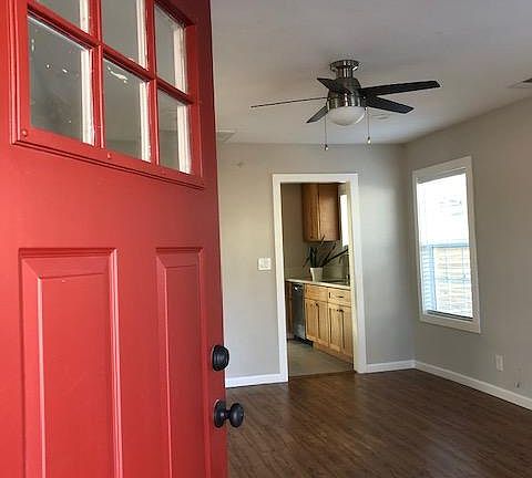 Enter into the living room with wood laminate flooring, ceiling fans, lots of natural light, designer two-tone paint