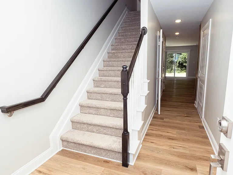 Entrance showing hallway to living space and kitchen as well as stairs that lead to bedrooms and bathroom.