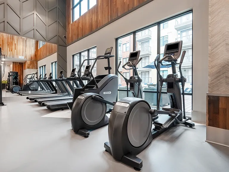 A Gym With Treadmills, A Stair Climber, And Elipticals