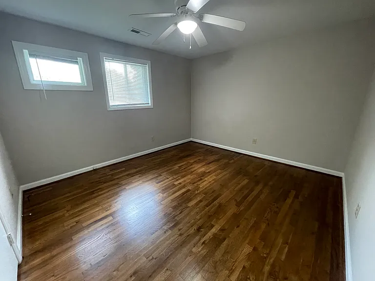 Primary bedroom with hardwood flooring and ceiling fan
