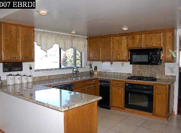 Open kitchen w/granite countertops, tile floors, and built-in appliances