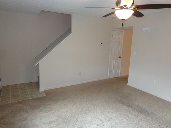 Living room looking at stairs to 2nd floor and kitchen hallway on right ,door is to half bath