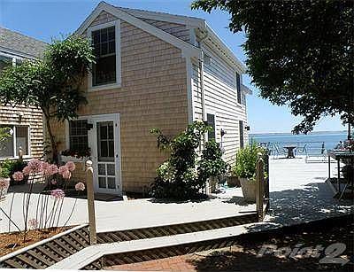 The cottage sits directly on the water ensconced by a deck and colorful planters.
