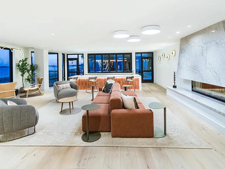 A spacious lounge with a statement fireplace, comfortable seating, and views just beyond.