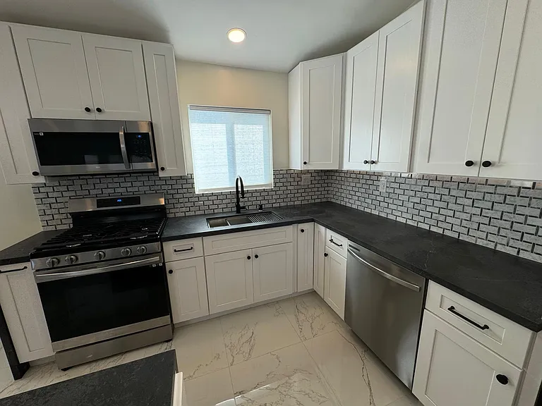 Kitchen with new SS appliances, quartz countertops, white shaker cabinets, workstation sink, island and under cabinet lighting.