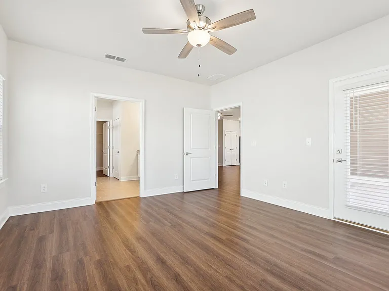 Bright bedroom featuring wood floors and a ceiling fan.