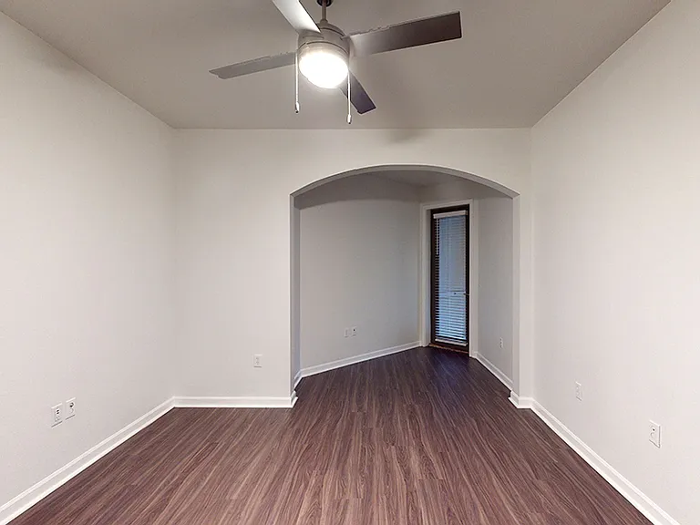 Spacious apartment bedroom with wood-style flooring.