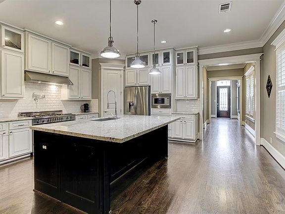 This gorgeous kitchen has granite counters, stainless appliances, tall maple cabinets with glass fronted uppers and soft close drawers, white subway tile backsplash, and an over-sized breakfast bar/island.