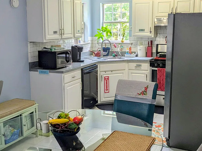 Eat-in kitchen with ample white cabinetry, tiled backsplash, and a window over the sink, plus space for a dining table.