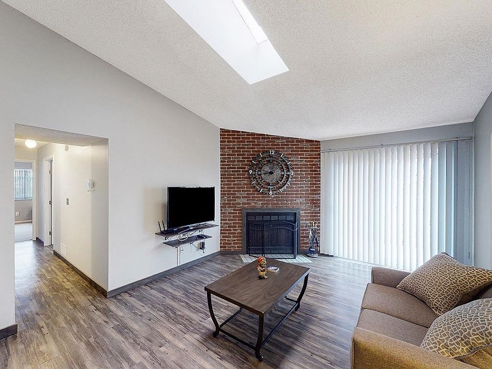 Grand living room includes a fireplace and balcony. Also space has high ceilings that includes ceiling window.