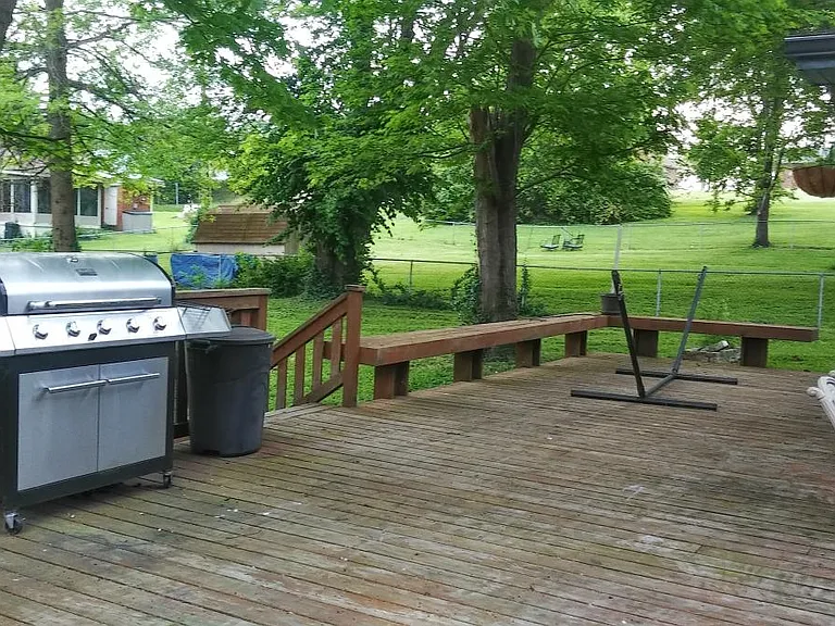 Fenced backyard with mature trees and a shed for extra storage.